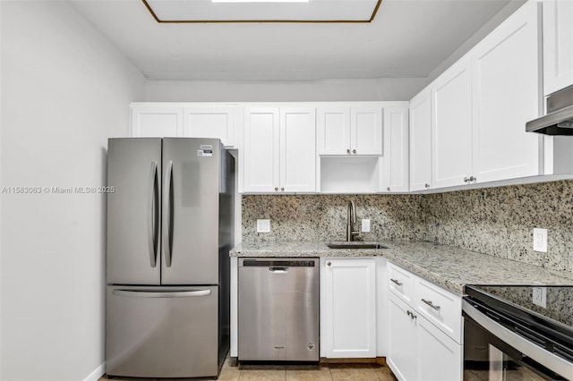 kitchen with appliances with stainless steel finishes, tasteful backsplash, light stone countertops, white cabinets, and sink