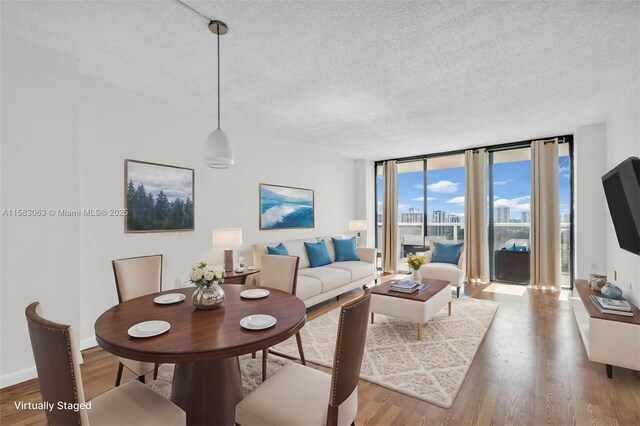 living room featuring light wood-type flooring, floor to ceiling windows, and a textured ceiling