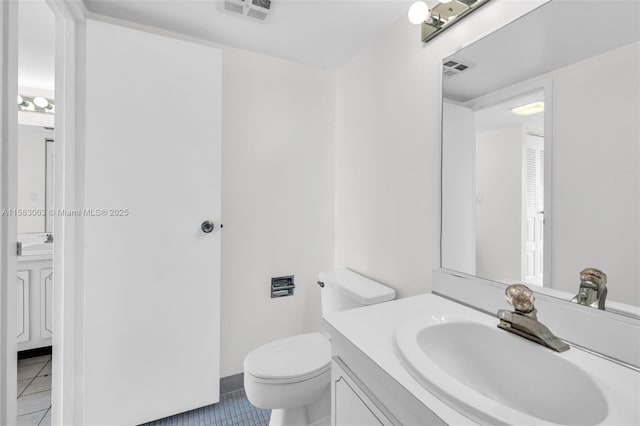 bathroom with toilet, vanity, and tile patterned flooring