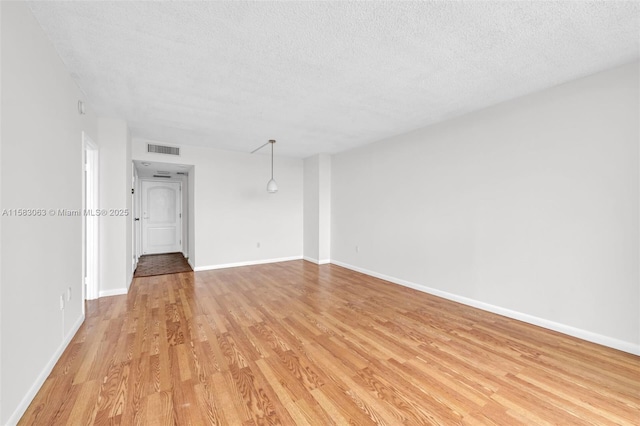 unfurnished room featuring a textured ceiling and light hardwood / wood-style floors