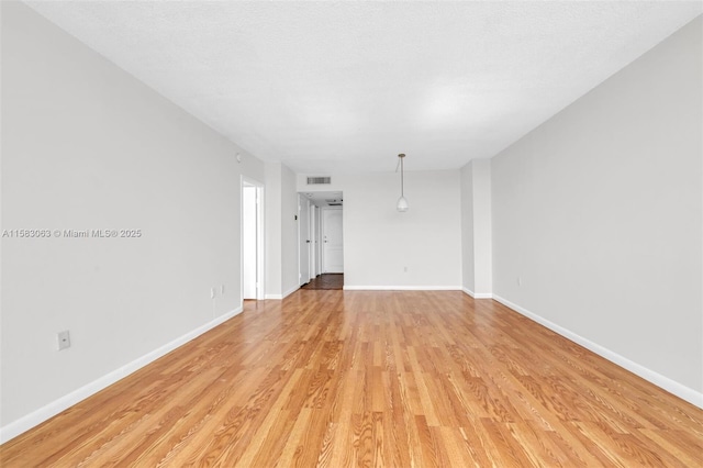 unfurnished living room featuring a textured ceiling and light hardwood / wood-style floors