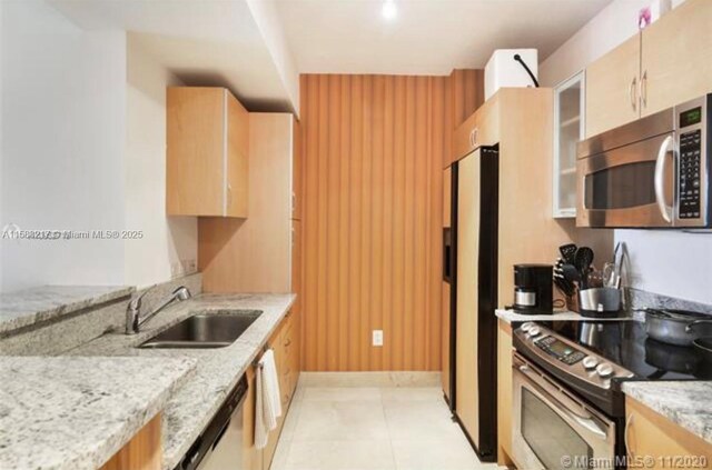 18800 NE 29th Ave Unit 520, Aventura, FL 33180 - kitchen featuring stainless steel appliances, a sink, light stone counters, glass insert cabinets, and light brown cabinets