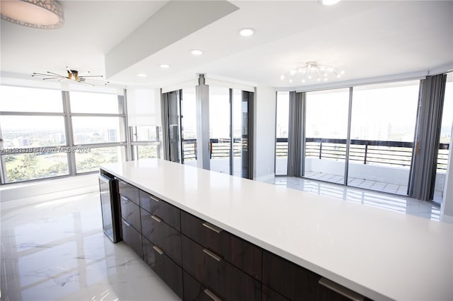 kitchen featuring ceiling fan, light tile floors, dark brown cabinets, expansive windows, and track lighting