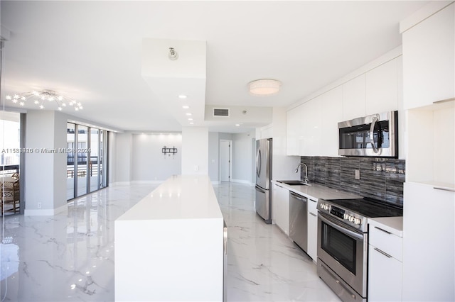 kitchen featuring sink, light tile flooring, backsplash, white cabinetry, and stainless steel appliances