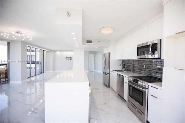 kitchen with white cabinets, backsplash, appliances with stainless steel finishes, light tile floors, and sink