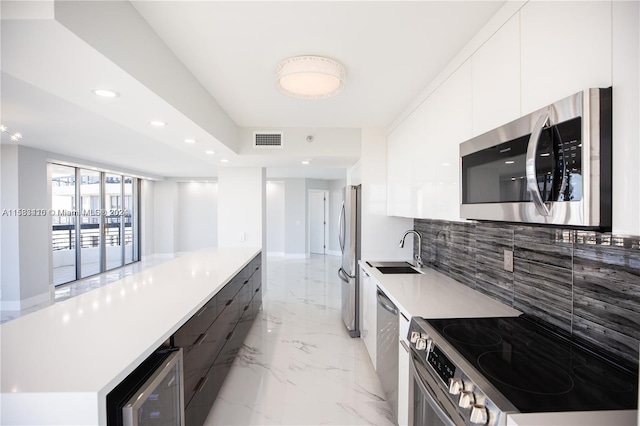 kitchen featuring white cabinets, light tile flooring, backsplash, appliances with stainless steel finishes, and sink