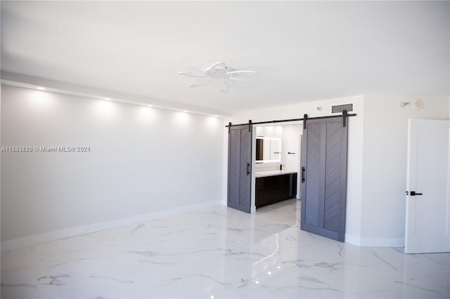 empty room featuring ceiling fan, light tile floors, and a barn door