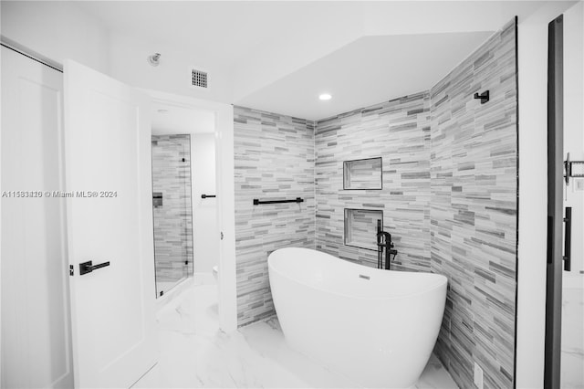 bathroom with a washtub, tile floors, and tile walls