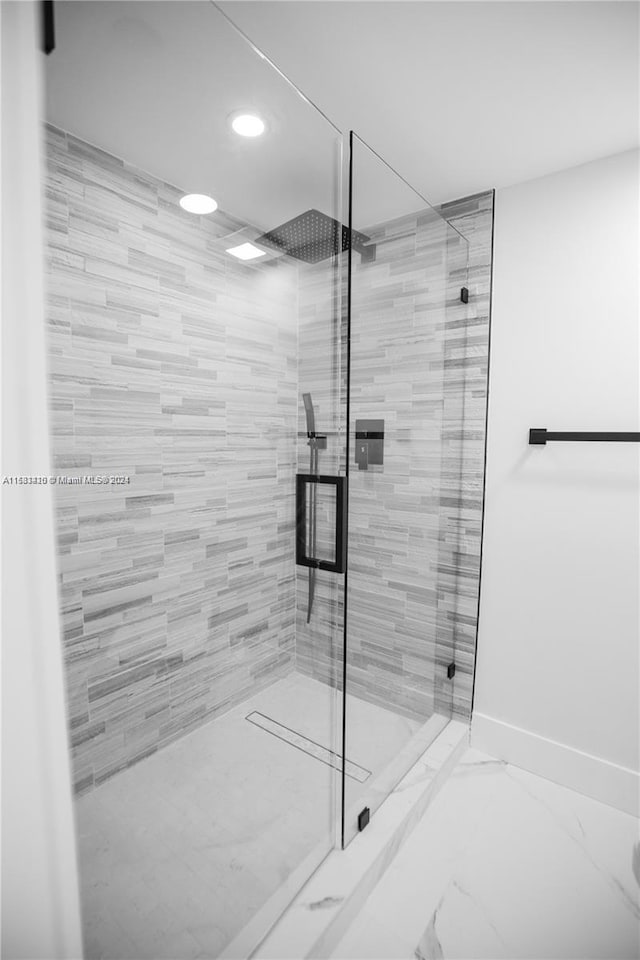 bathroom with a shower with door and tile flooring