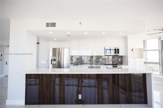 kitchen with sink, tasteful backsplash, white cabinetry, stainless steel appliances, and a kitchen breakfast bar