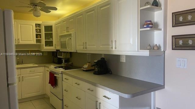 kitchen with light tile patterned flooring, white appliances, a ceiling fan, white cabinetry, and light countertops