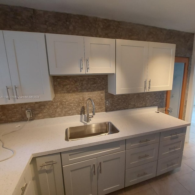 kitchen with light tile patterned flooring, sink, and light stone counters