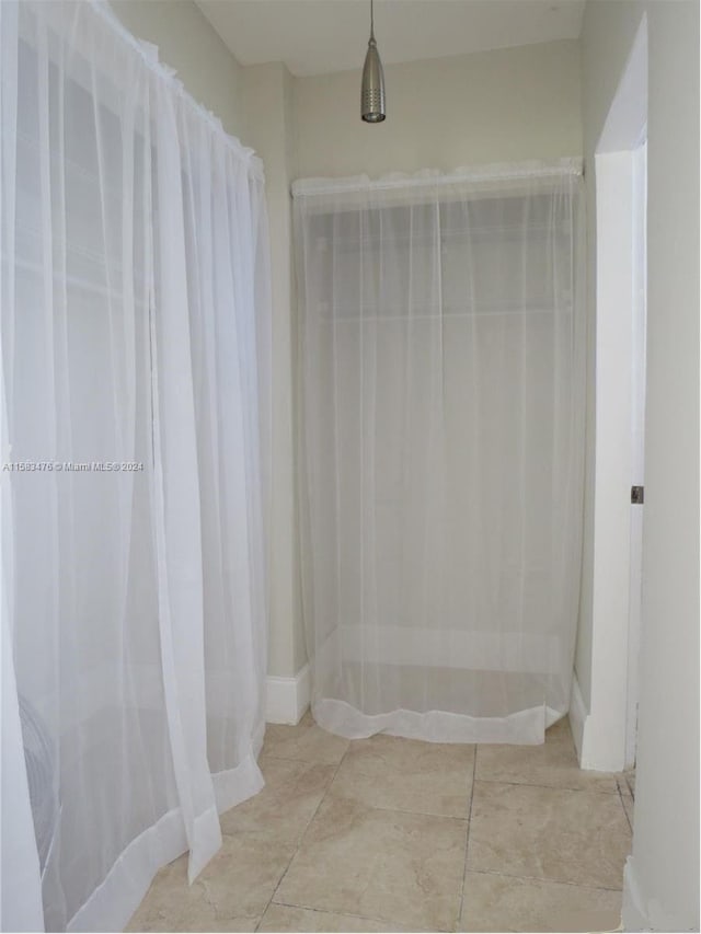 bathroom with a shower with shower curtain and tile patterned floors