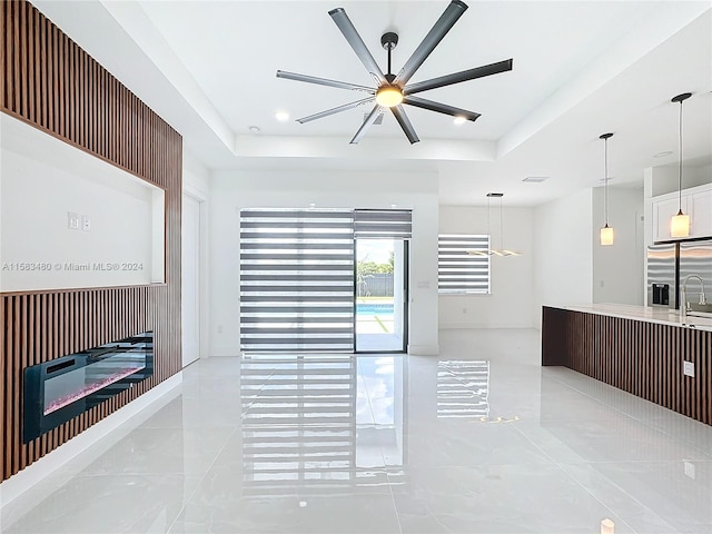 tiled living room featuring sink, ceiling fan, and a raised ceiling