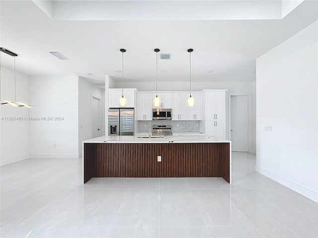 kitchen featuring appliances with stainless steel finishes, light tile floors, an island with sink, and white cabinetry