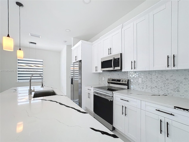 kitchen with appliances with stainless steel finishes, white cabinets, sink, backsplash, and hanging light fixtures