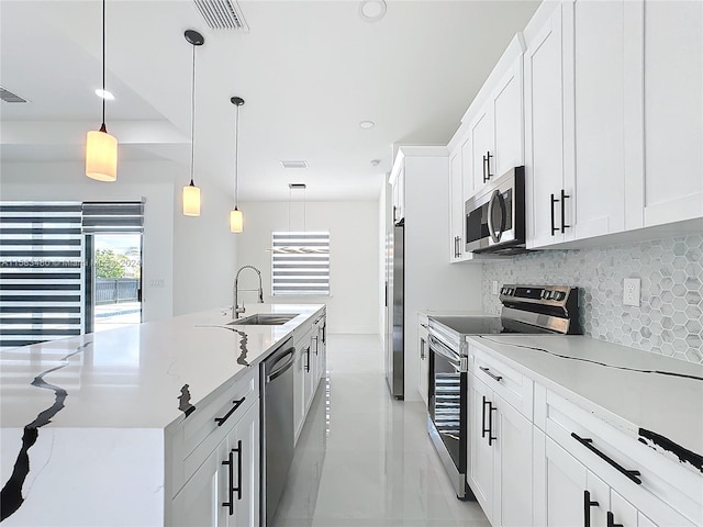 kitchen featuring pendant lighting, backsplash, stainless steel appliances, sink, and light tile floors