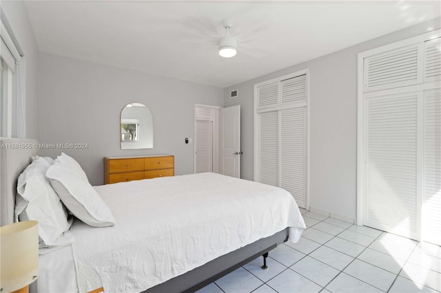 tiled bedroom featuring two closets and ceiling fan