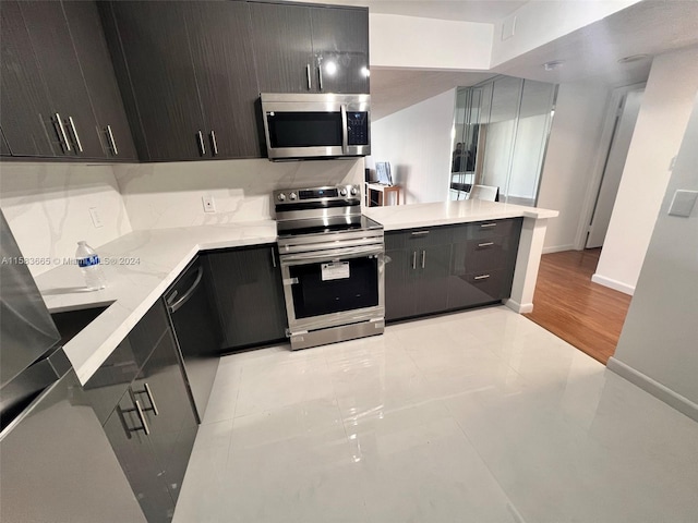 kitchen featuring dark brown cabinets, stainless steel appliances, kitchen peninsula, and light tile flooring