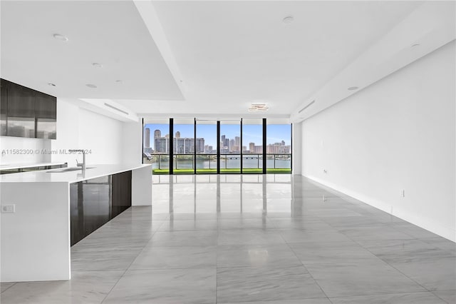 kitchen featuring light tile floors, a wall mounted air conditioner, sink, expansive windows, and a center island with sink