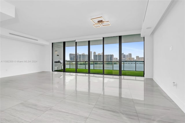 empty room featuring a water view, expansive windows, and light tile flooring