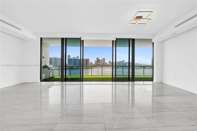 empty room with a healthy amount of sunlight, expansive windows, and light tile flooring