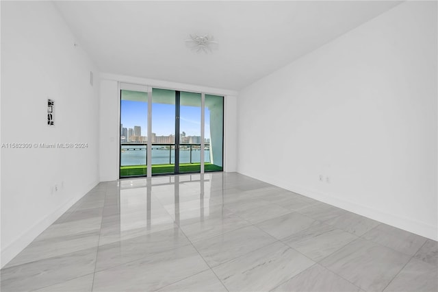 tiled spare room featuring expansive windows and a water view