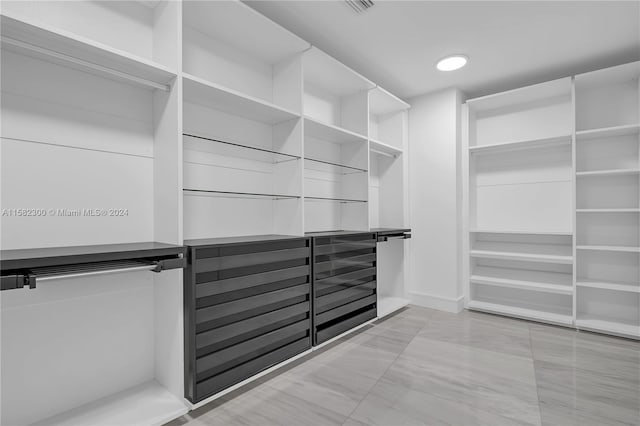 walk in closet with light tile floors