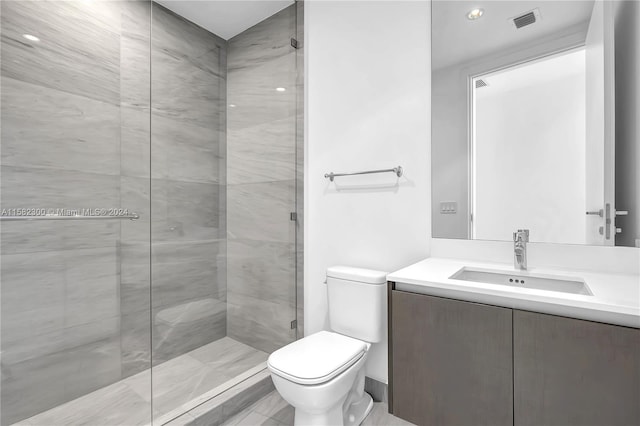 bathroom featuring toilet, vanity, and a tile shower