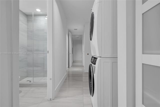 hallway featuring stacked washer and clothes dryer and light tile flooring