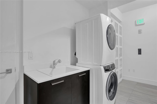 clothes washing area featuring sink, stacked washing maching and dryer, and light tile floors