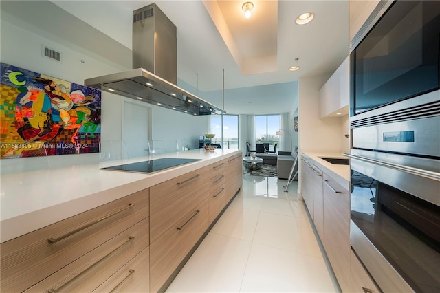 kitchen featuring appliances with stainless steel finishes, light brown cabinets, light tile flooring, and island range hood