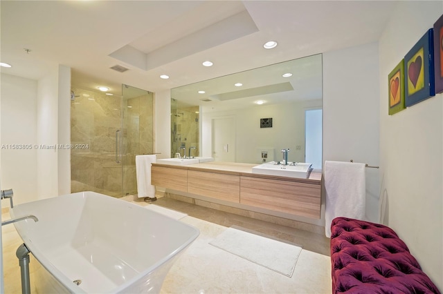 bathroom with tile flooring, a raised ceiling, separate shower and tub, and dual bowl vanity