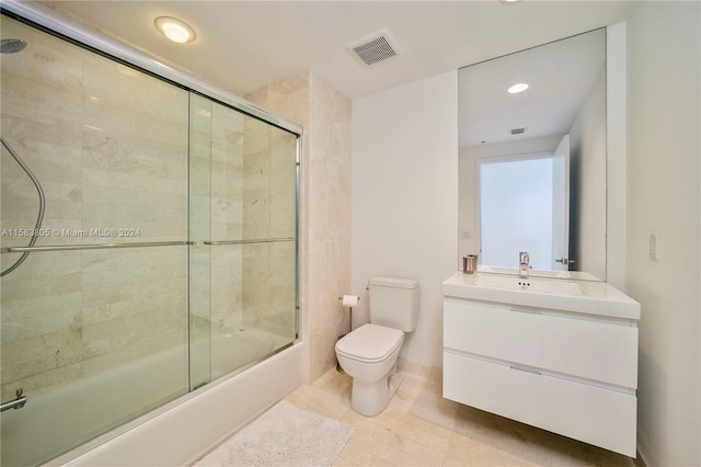 full bathroom featuring vanity, tile floors, toilet, and bath / shower combo with glass door