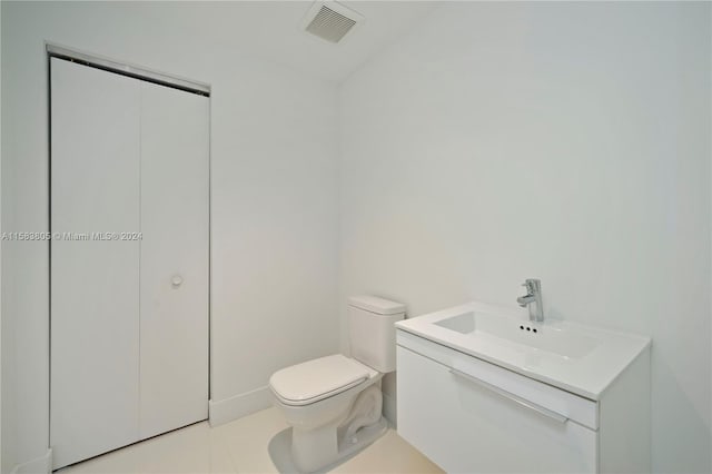 bathroom with toilet, tile floors, and vanity