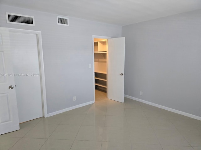 unfurnished bedroom with a spacious closet, a closet, and light tile patterned flooring