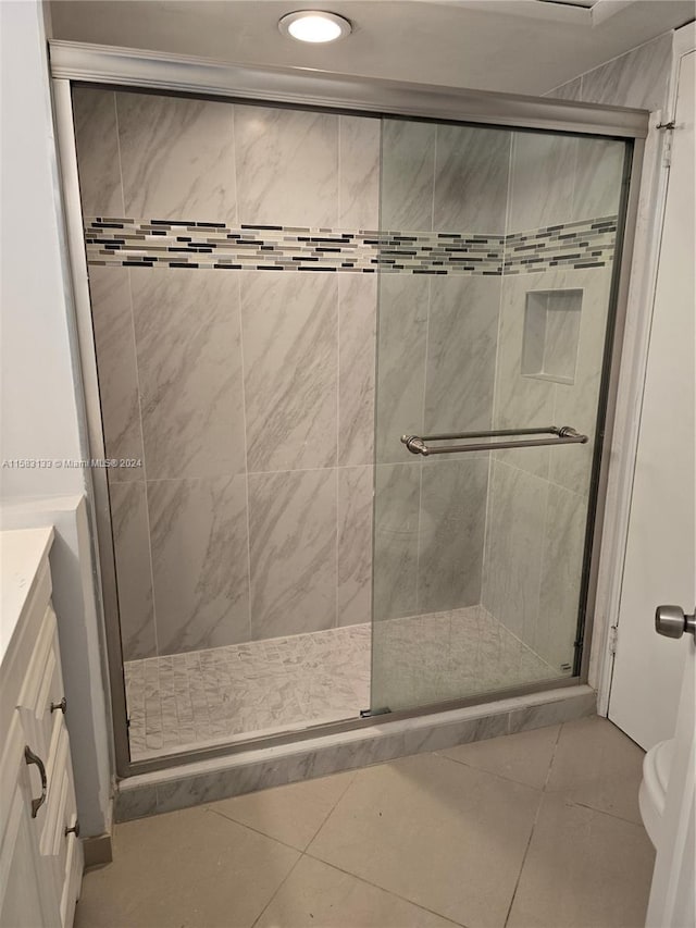 bathroom with tile patterned flooring, vanity, and walk in shower