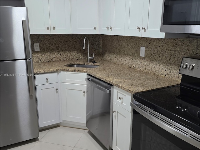 kitchen featuring decorative backsplash, light stone countertops, stainless steel appliances, sink, and white cabinets