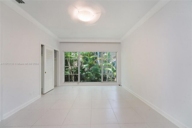 unfurnished room featuring crown molding and light tile floors