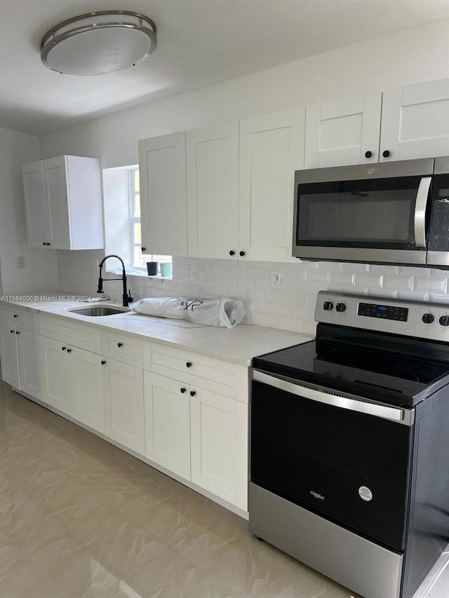 kitchen with sink, light tile floors, white cabinetry, and appliances with stainless steel finishes