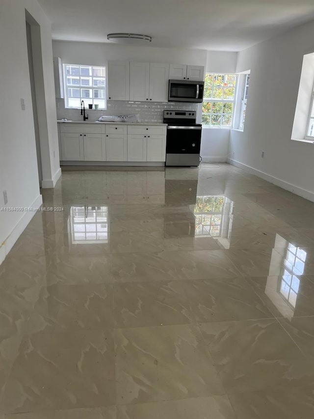 kitchen featuring white cabinets, stainless steel appliances, tasteful backsplash, tile flooring, and sink