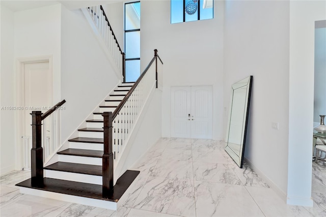 entryway featuring a towering ceiling and light tile flooring