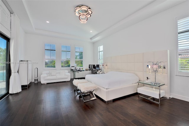 bedroom with a chandelier, dark hardwood / wood-style floors, and a tray ceiling