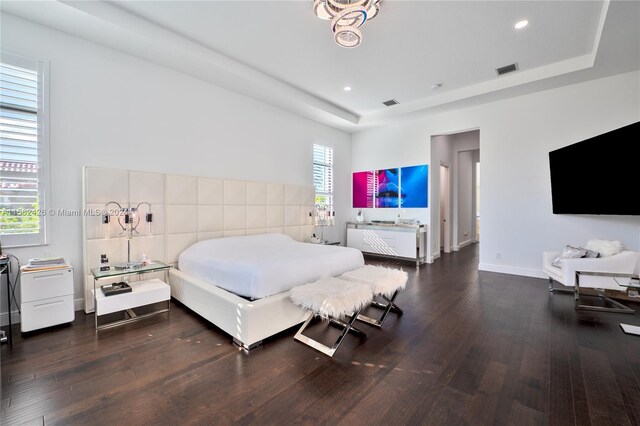 bedroom with dark hardwood / wood-style floors and a raised ceiling