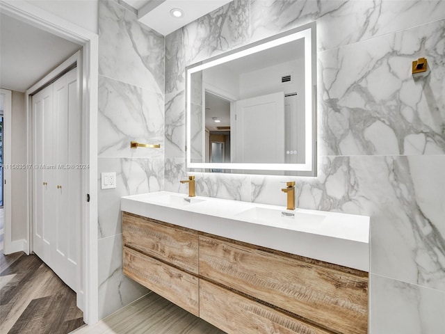 bathroom with tile walls, hardwood / wood-style flooring, and dual bowl vanity