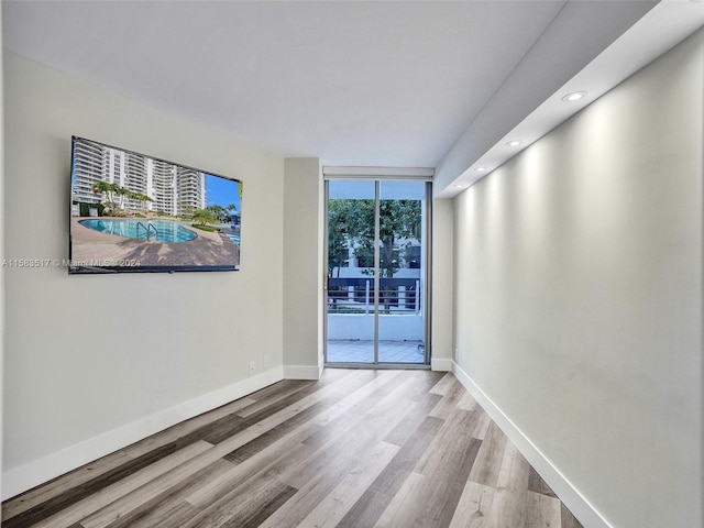 spare room with a wall of windows and hardwood / wood-style floors