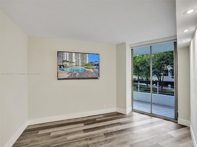 empty room featuring floor to ceiling windows and light hardwood / wood-style floors