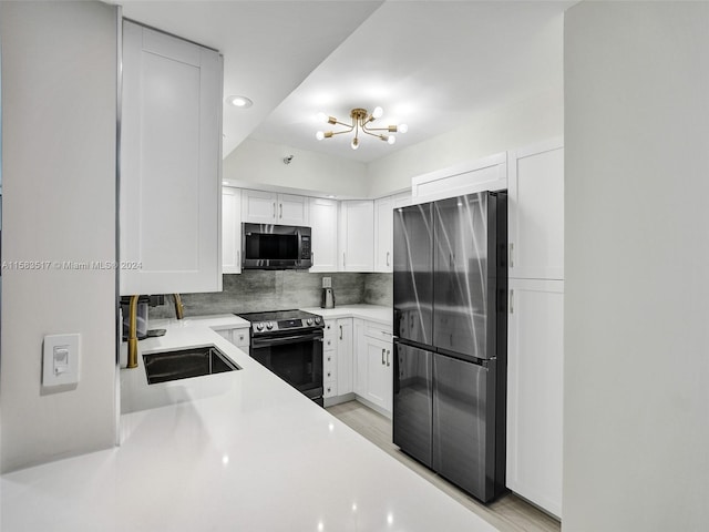 kitchen with electric range oven, black refrigerator, tasteful backsplash, and white cabinetry