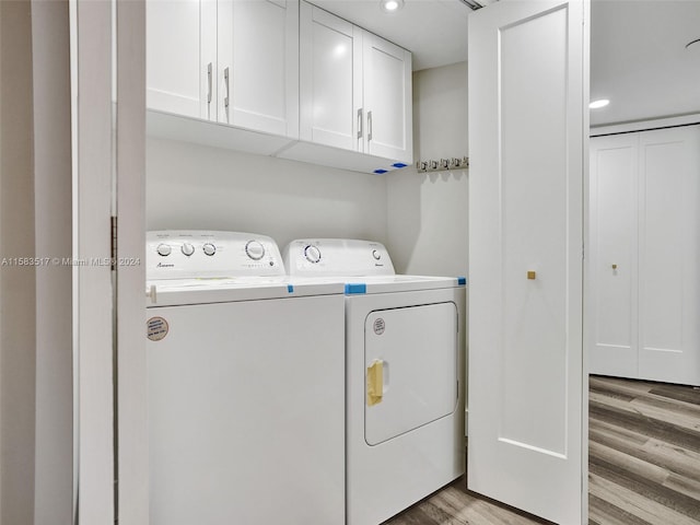 washroom with light hardwood / wood-style flooring, separate washer and dryer, and cabinets