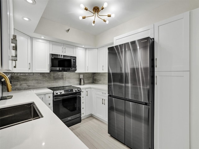 kitchen with appliances with stainless steel finishes, light hardwood / wood-style flooring, backsplash, white cabinetry, and sink